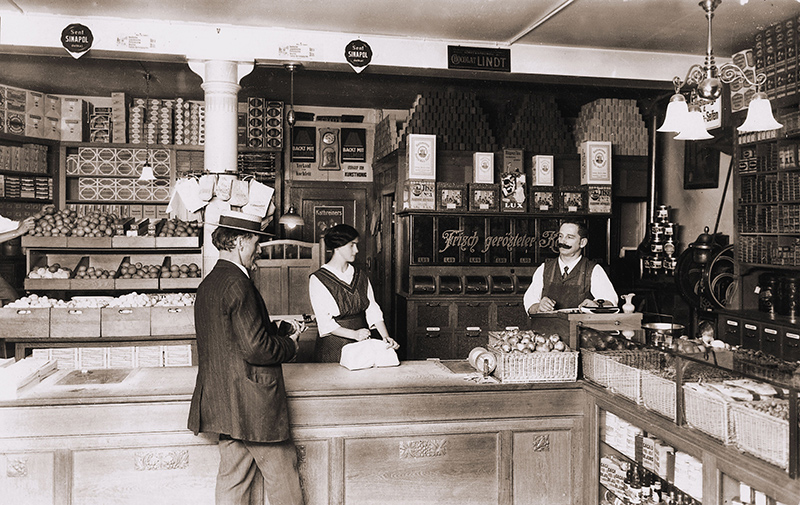 ZürichFenster, Gschäfte in Züri, Heinrich Schwarzenbach II mit einer Angestellten und einem Kunden im Laden an der Münstergasse um 1920, Copyright Sammlung Schwarzenbach 